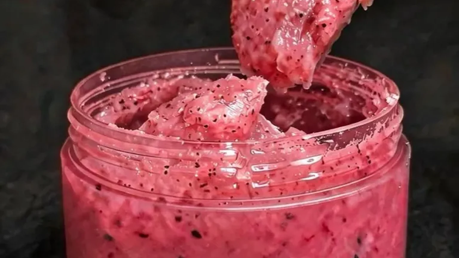 Body scrub texture showing coarse exfoliating granules in an open 230g jar