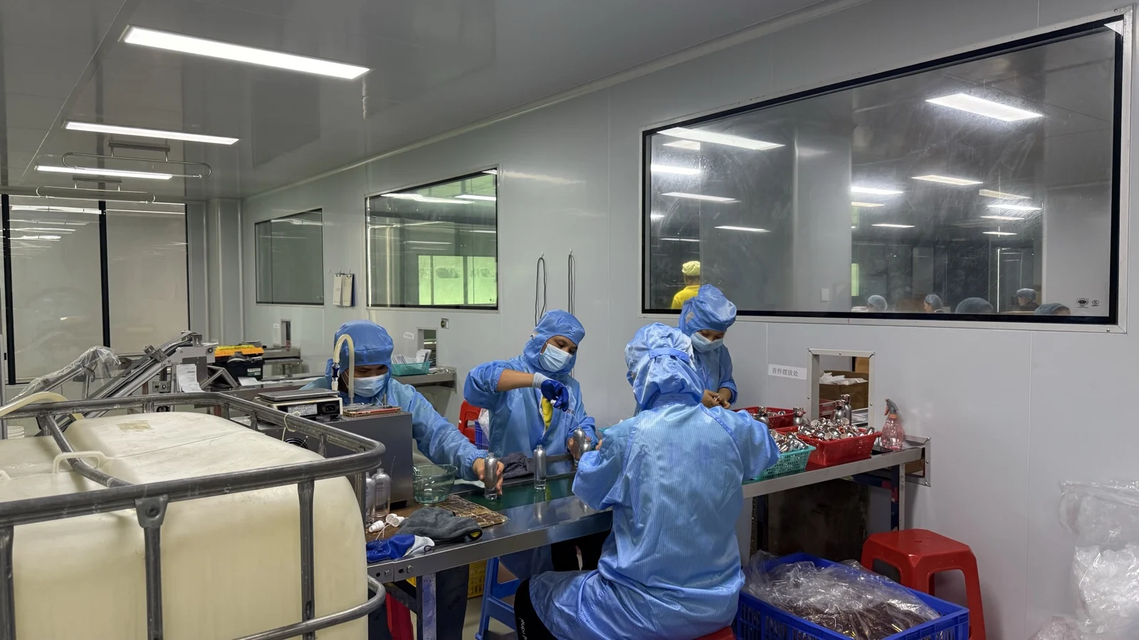 Operators in cleanroom gowning assembling pumps on the filling line at an ISO 22716 and GMPC certified Guangzhou cosmetics factory